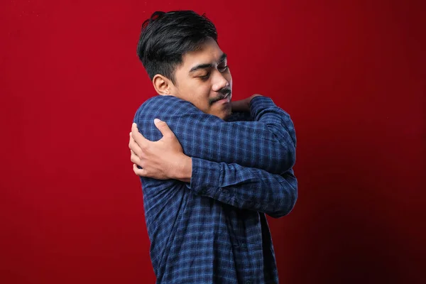 Joven Hombre Guapo Sobre Fondo Rojo Aislado Abrazándose Feliz Positivo —  Fotos de Stock