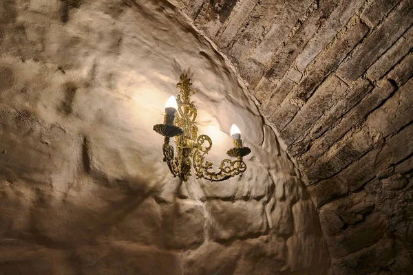 城のアンティーク石の壁に2本のろうそくがついた黄金の燭台 ロシア — ストック写真