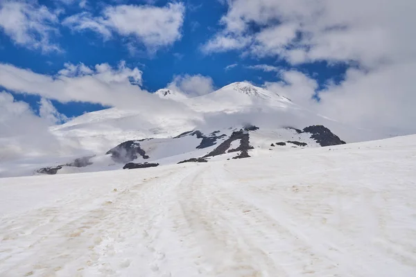 snow-capped peaks bright sun and white clouds over the peaks of the Caucasus mountains