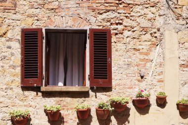 Volterra 'da duvarında çiçek saksıları olan bir evin penceresi, Toskana, İtalya
