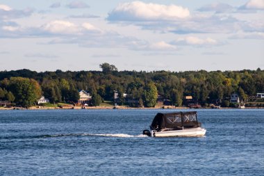 Brockville, Ontario, Canada - September 19, 2020: A covered recreational motorboat travels along the St. Lawrence River