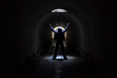 Karanlık bir yeraltı tünelinde bir adam bir çıkış yolu arıyor ve yardım istemek için ellerini havaya kaldırıyor..