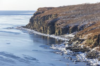 Rusya 'nın Vladivostok adasındaki Tobizin Burnu' nun kayalık kıyıları güneşli bir kış gününde kar ve yüzen buzla kaplıydı..
