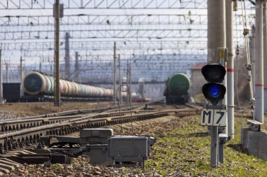 Vladivostok, Rusya - 24 Nisan 2020: Vladivostok 'taki Trans-Sibirya Demiryolu' nun sonundaki bir yük istasyonunda petrol ürünleriyle dolu demiryolu tanklarının arka planına karşı mavi bir sinyal taşıyan bir semfore.