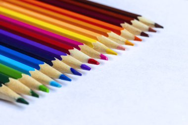 Renkli kalemler beyaz kağıt üzerinde bir sırada yatıyor..