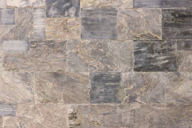 Binanın duvarı çeşitli renk ve boyutlarda cilalanmış mermer levhalarla karşılaşıyor.. 