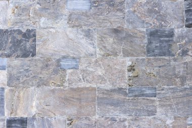 Binanın duvarı çeşitli renk ve boyutlarda cilalanmış mermer levhalarla karşılaşıyor.. 