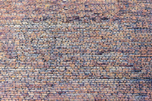 A huge solid brick wall with no windows. Old, cracked masonry, coated with deposits and grime.