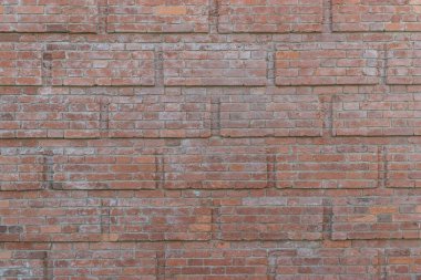 Yıpranmış ve solmuş yüzeyi olan eski, çatlak tuğlalardan oluşan bir duvar. Eski bir evin yenilenmiş tuğlası..