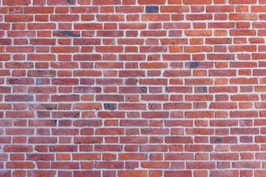 Yıpranmış ve solmuş yüzeyi olan eski, çatlak tuğlalardan oluşan bir duvar. Eski bir evin yenilenmiş tuğlası..