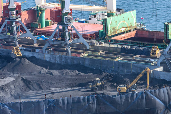 Владивосток, Россия - 05 октября 2019 года: Перевалка карьерного угля в порту Владивосток. Экологические проблемы от угольной пыли на угольных терминалах Дальнего Востока России.