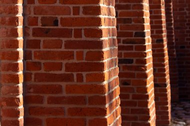 Aralıkları ve çıkıntılı parçaları olan geniş eski bir tuğla duvar..