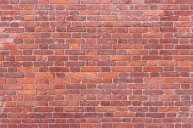 Yıpranmış ve solmuş yüzeyi olan eski, çatlak tuğlalardan oluşan bir duvar. Eski bir evin yenilenmiş tuğlası..