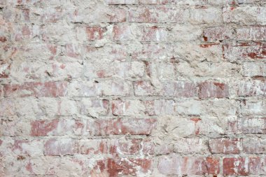 Yaşlılıktan kalma alçıyla kaplı tuğla bir duvar. Rüzgarın ve yağışın inşaat malzemeleri üzerindeki etkisi.