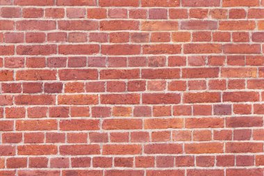 Yıpranmış ve solmuş yüzeyi olan eski, çatlak tuğlalardan oluşan bir duvar. Eski bir evin yenilenmiş tuğlası..