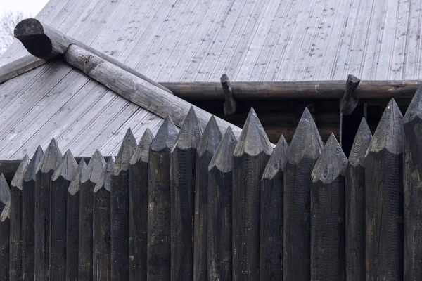 A protective palisade around a wooden log house in a Russian village. Traditional Russian construction of huts.