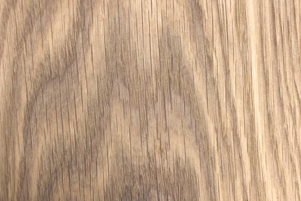 An oak kitchen chopping board covered in knife scratches. Uneven texture of a polished board with a pattern and streaks of natural wood.