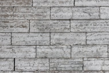 Dikdörtgen mermer bloklardan yapılmış gri taş bir duvarın dokusu. Duvarda güneş ışığı.