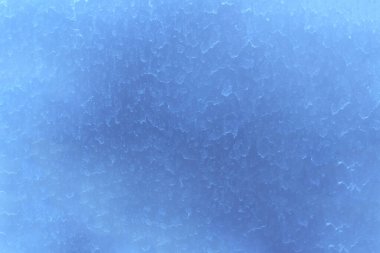 Kirli pencere camının yüzeyi, tozlu yağmur damlalarıyla kaplı. Mavi bulanık soyut doku.
