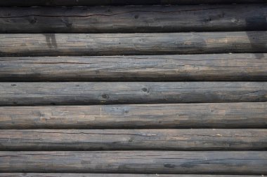 Koyu renkte yıpranmış odunlardan yapılmış eski bir ahşap evin duvarı. Geleneksel Rus kütük kulübesi.