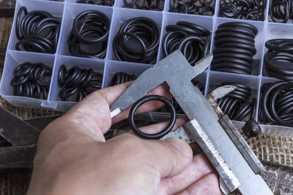 Lastik halkanın çapını kalibre ile ölçüyorum. Bir adam elinde eski bir ölçü aleti tutuyor..