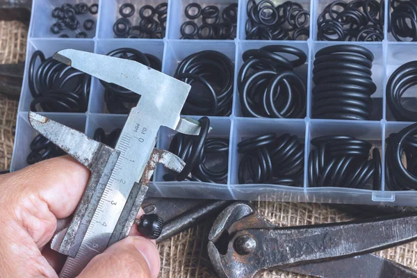 Lastik halkanın çapını kalibre ile ölçüyorum. Bir adam elinde eski bir ölçü aleti tutuyor..