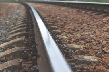 Demiryolu rayları ve pusucular yakın plan. Uzakta bir virajı dönen bir demiryolu..
