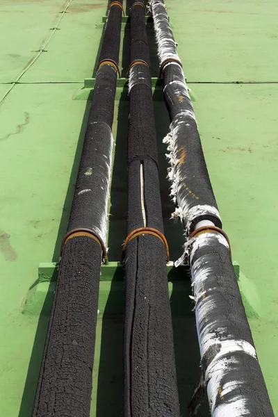 Oude pijp lijn voor waterkoeling cover met zwart schuim op groene vloer — Stockfoto
