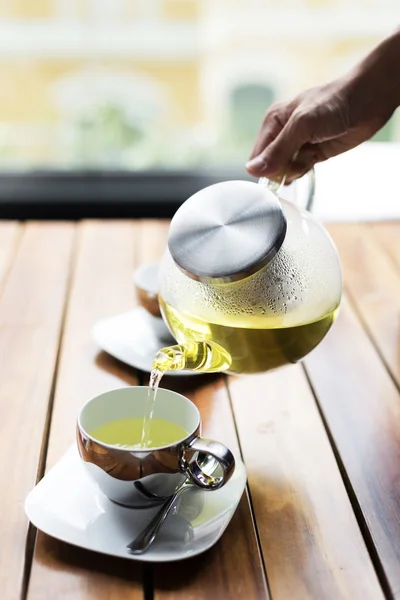 Tea pouring to teacup on table