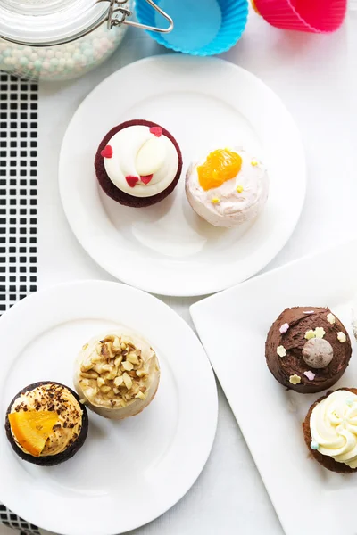 Färgglada läckra muffins på tallrikar, ovanifrån — Stockfoto