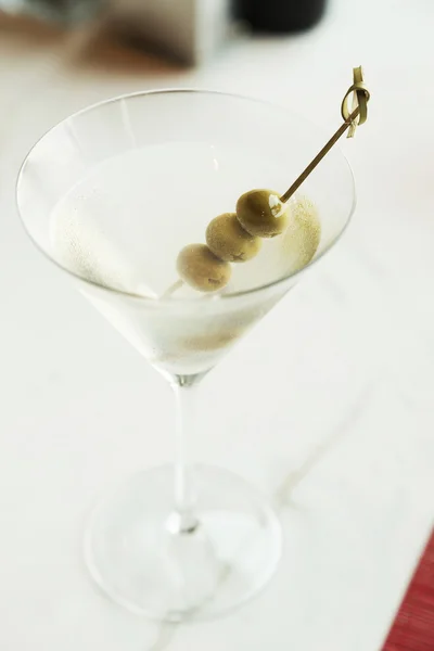 Dry martini med gröna oliver på bord — Stockfoto