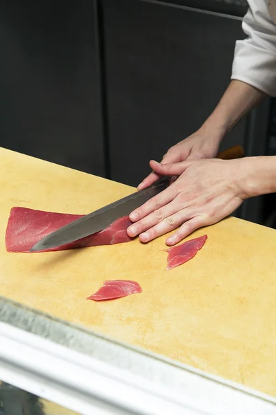 Mano con cuchillo cortando carne de atún para hacer sushi —  Fotos de Stock