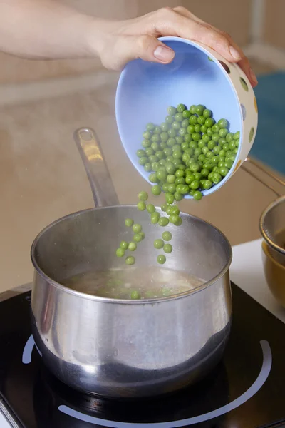 Hand adding pea into pot for making pea soup — Stock Photo, Image