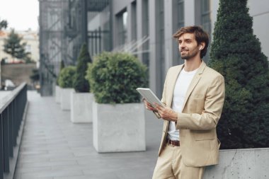 Başarılı iş adamı sokakta duruyor ve online çalışma toplantısı için dijital tablet kullanıyor. Sakallı erkek, modern cihazda görüntülü konuşma yapıyor..