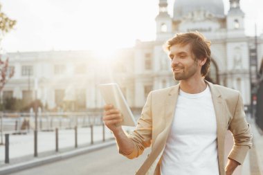 Resmi kıyafetler giymiş, elinde dijital tabletle toplu taşıma durağında poz veren heyecanlı sakallı turist. Genç işadamı New City 'de iş gezisinin tadını çıkarıyor.