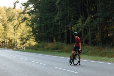 Korumalı kasklı ve gözlüklü profesyonel bisikletçi kaldırımlı yolda dikilip arkasına bakıyor. Spor kıyafetli yorgun adam yeşil ormanın arasında dolaşırken derin bir nefes alıyor..