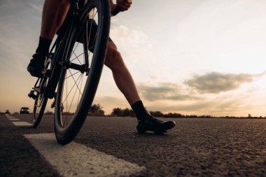 Uzun bir temiz hava yolculuğundan sonra spor kıyafetleri içinde bisiklet süren profesyonel bisikletçinin düşük açılı görüntüsü. Kaslı erkek bacaklarına odaklan. Eğlence anlayışı..