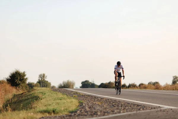 Muscular man in protective helmet having long distance ride during morning time. Beautiful nature around. Outdoors activity.