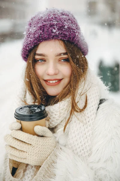雪の中 路上に立ちながら熱いコーヒーと茶色の髪の暖かい手を持つ幸せな若い女性の肖像画 居心地の良い雰囲気と冬の時間の概念 — ストック写真