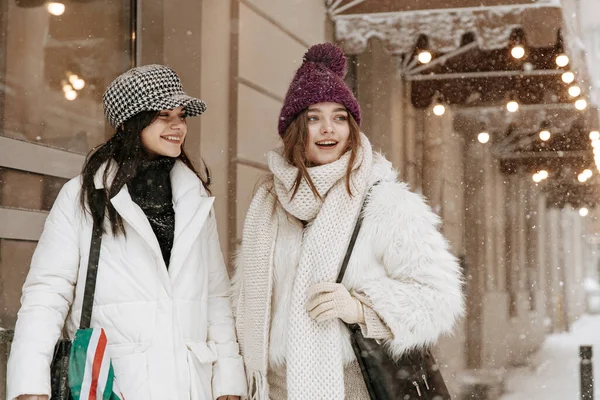 雪の秋の間に街の通りに立って暖かい冬服の2つの幸せな若い女性のグループ 笑顔の女性の友人は冬の時間帯に一緒に外を歩くレジャー時間を過ごす — ストック写真