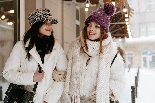 白いコートを着た素晴らしい若い女性 暖かい帽子 ニットスカーフは冬の間通りを一緒に歩いています 新鮮な空気で休暇中にリラックスした笑顔の女性 — ストック写真