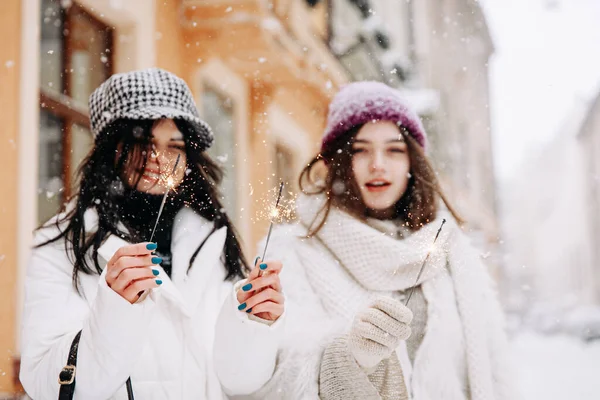 雪の日には外の輝きを使って暖かい服を着た陽気な若い女性 冬休みに路上でカメラを構える2人の友人 — ストック写真