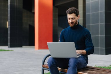 Genç işadamı dizüstü bilgisayarında internette sörf yapıyor