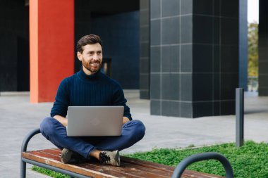Kendine güvenen iş adamı kablosuz bilgisayarı açık havada kullanıyor.
