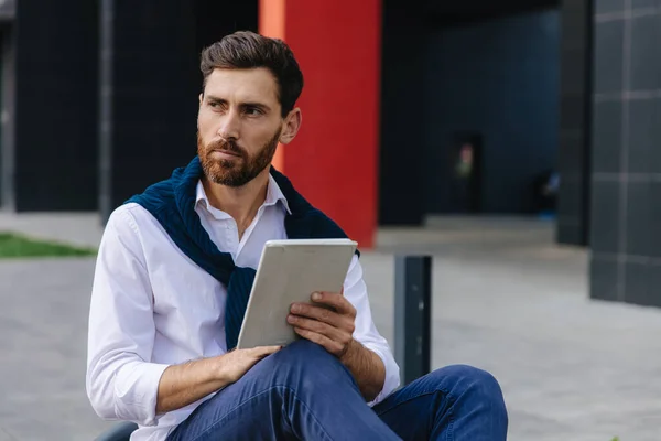 Busy man working on digital tablet outside his office