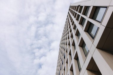 Mavi gökyüzünün üstündeki yüksek modern binanın alçak açılı görüntüsü. Gökdelenin dış tarafı. Mimarlık kavramı.