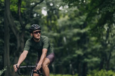 Sağlıklı ve kasklı sağlıklı bir adam ve temiz havada bisiklet süren aynalı gözlükler. Kafkasyalı aktif adam düzenli olarak açık havada antrenman yapıyor. Favori hobi konsepti.