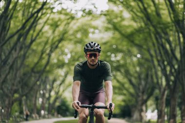 Kasklı ve aynalı gözlüklü güçlü beyaz adamın sabahları temiz havada bisiklet sürmek için harcadığı görüntüler. Erkek sporcuların açık hava aktiviteleri. Bisiklet kavramı.