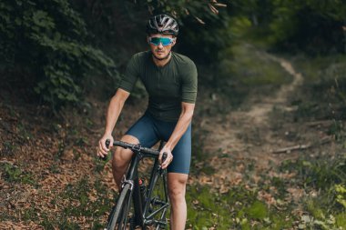 Spor elbiseli, kasklı ve gözlüklü beyaz bir adam sabah vaktini şehir parkında antrenman için harcıyor. Kaslı adam açık havada en sevdiği aktif hobiyi yapıyor..