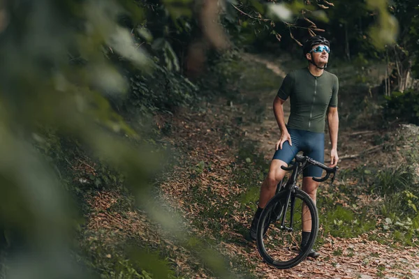 Hombre con casco y gafas sentado en bicicleta y sonriendo
